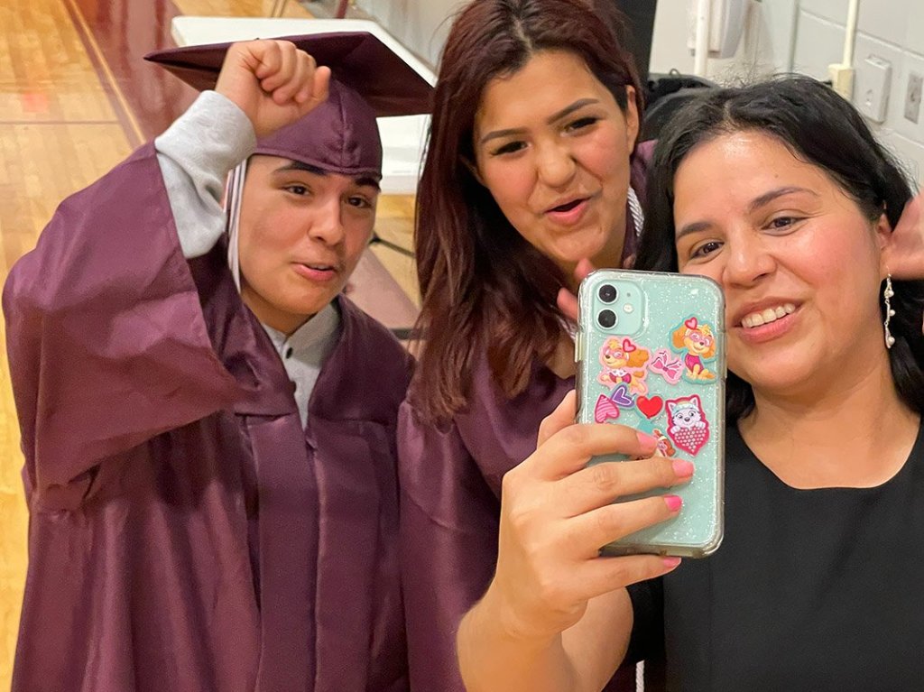 Graduates and a staff member taking a selfie before commencement